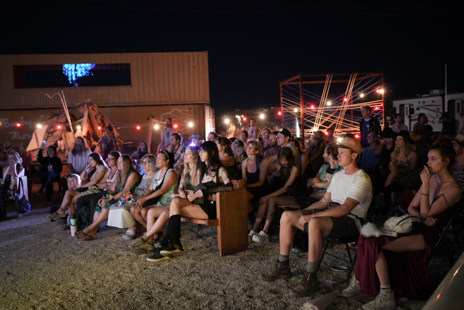 Audience at Bombay Beach Biennale under string lights